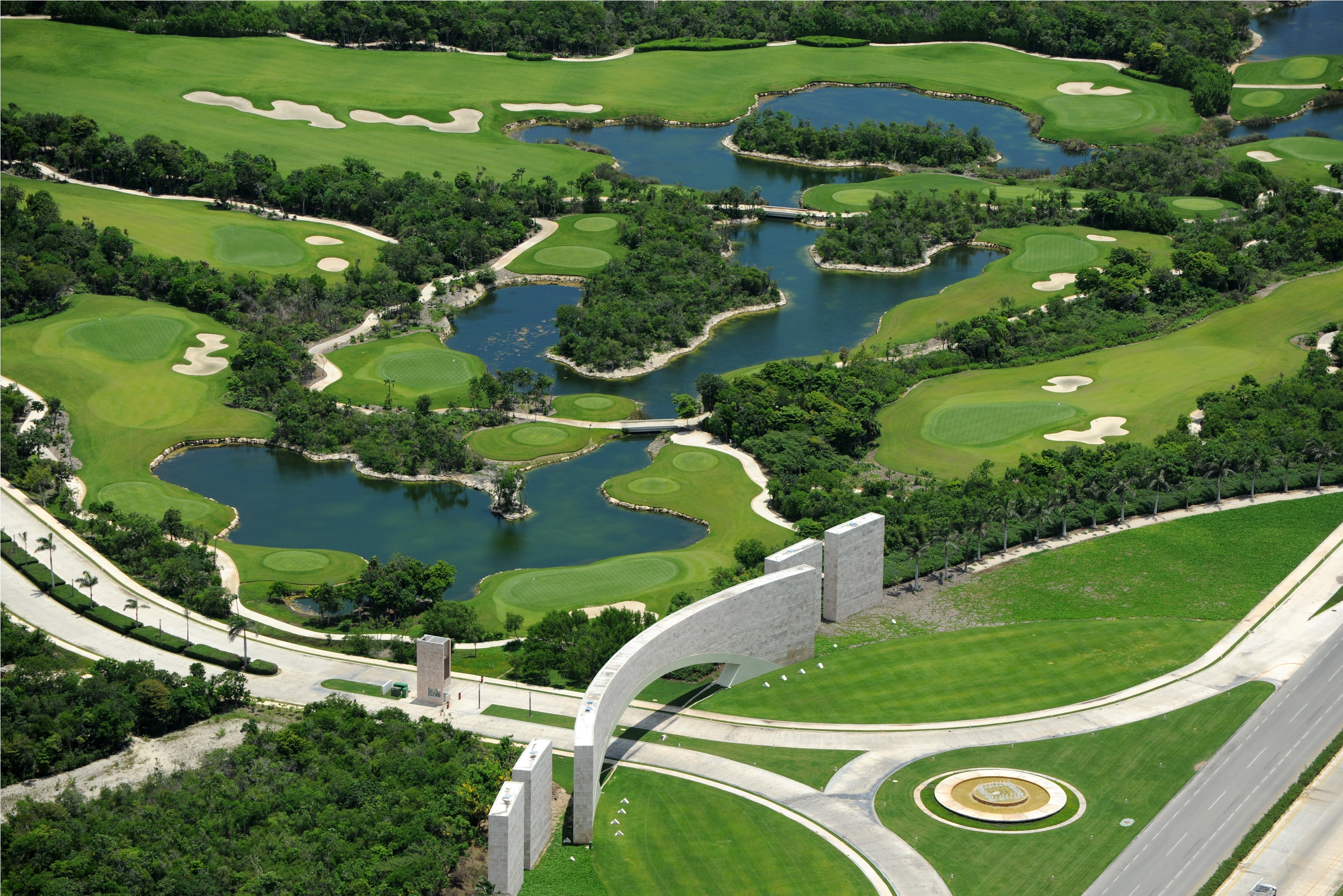 Acceso principal de Tulum Country Club con campo de golf y lagunas alrededor